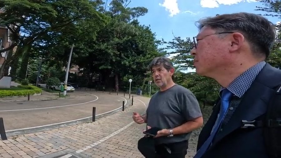 최준영과 Jorge Pérez Jaramillo가 함께 리버파크를 걸으며 대화하는 장면